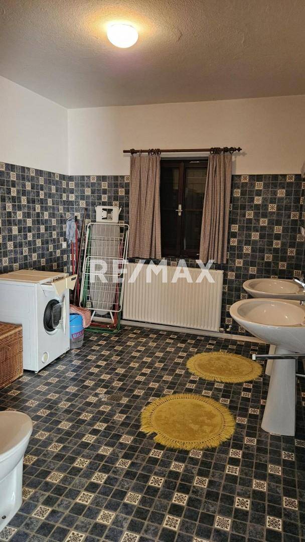 Geräumiger Waschraum mit Waschmaschine, Doppelwaschbecken und gemusterten Fliesen.