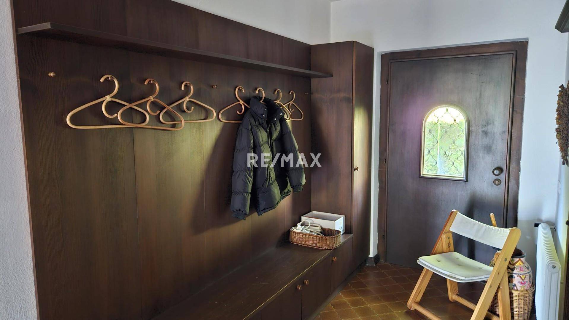 Eingangsbereich mit integrierter Garderobe und rustikaler Holztür mit Buntglasfenster.