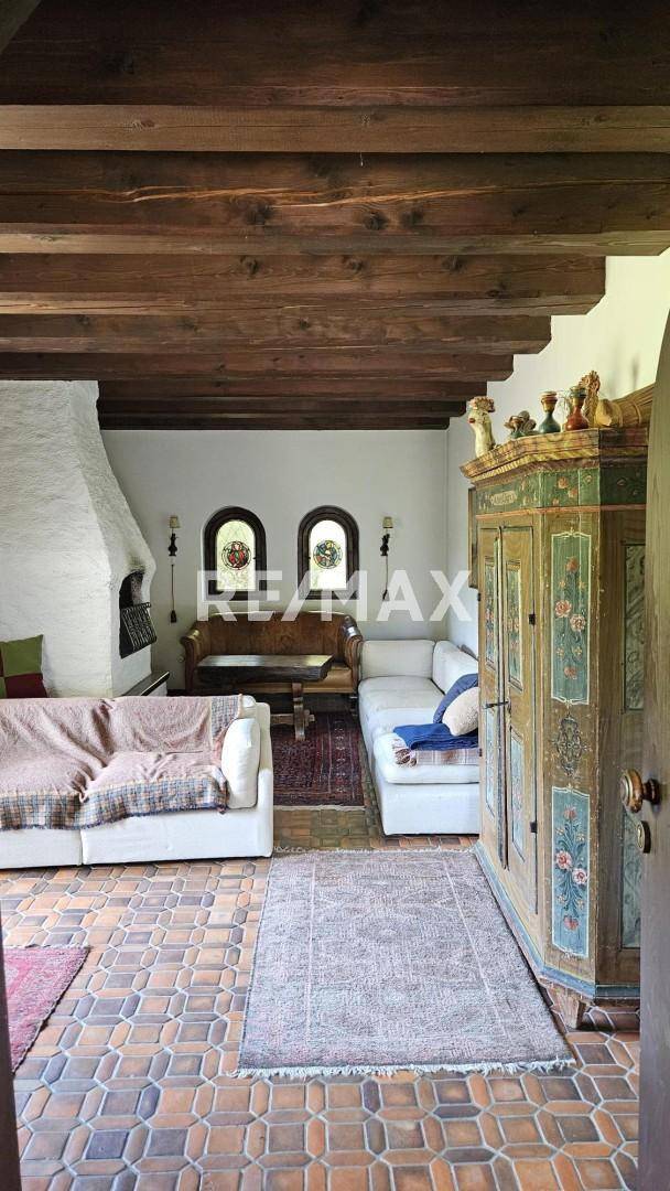 Rustikales Wohnzimmer mit Holzbalkendecke, Kamin und traditionellen Möbeln.