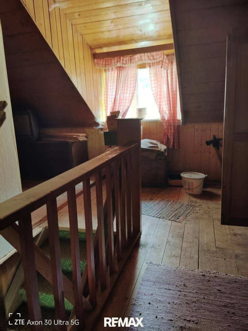 Dachgeschossraum mit Holzvertäfelung, schrägen Wänden und Fenster.