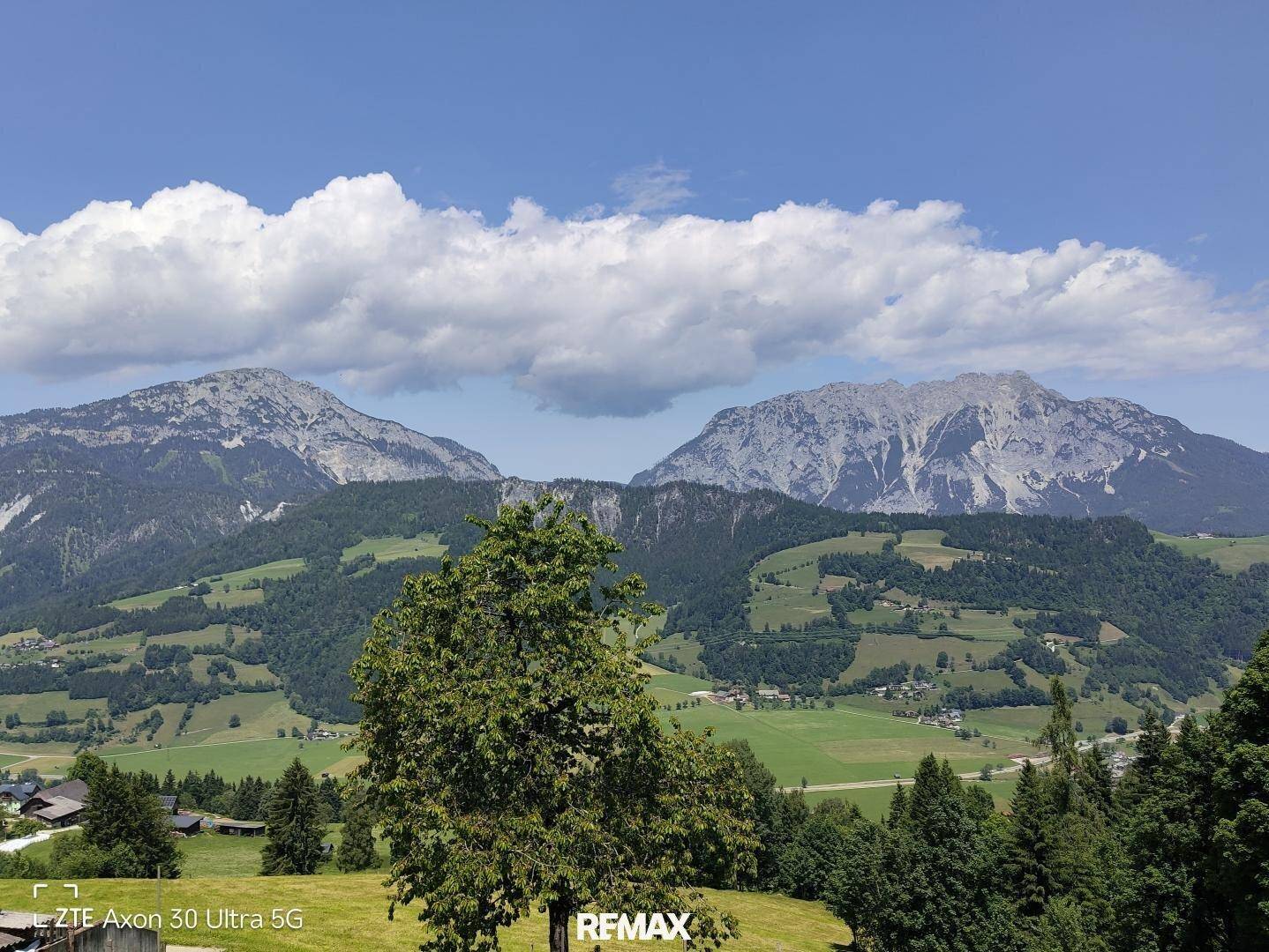 Malerische Berglandschaft mit grünen Hügeln und vereinzelten Wolken am Himmel.