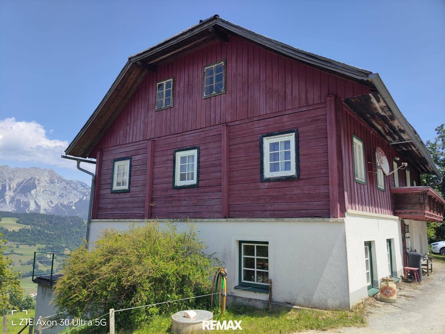 Seitenansicht eines traditionellen Holzhauses mit roten Fassaden und weißen Fenstern.