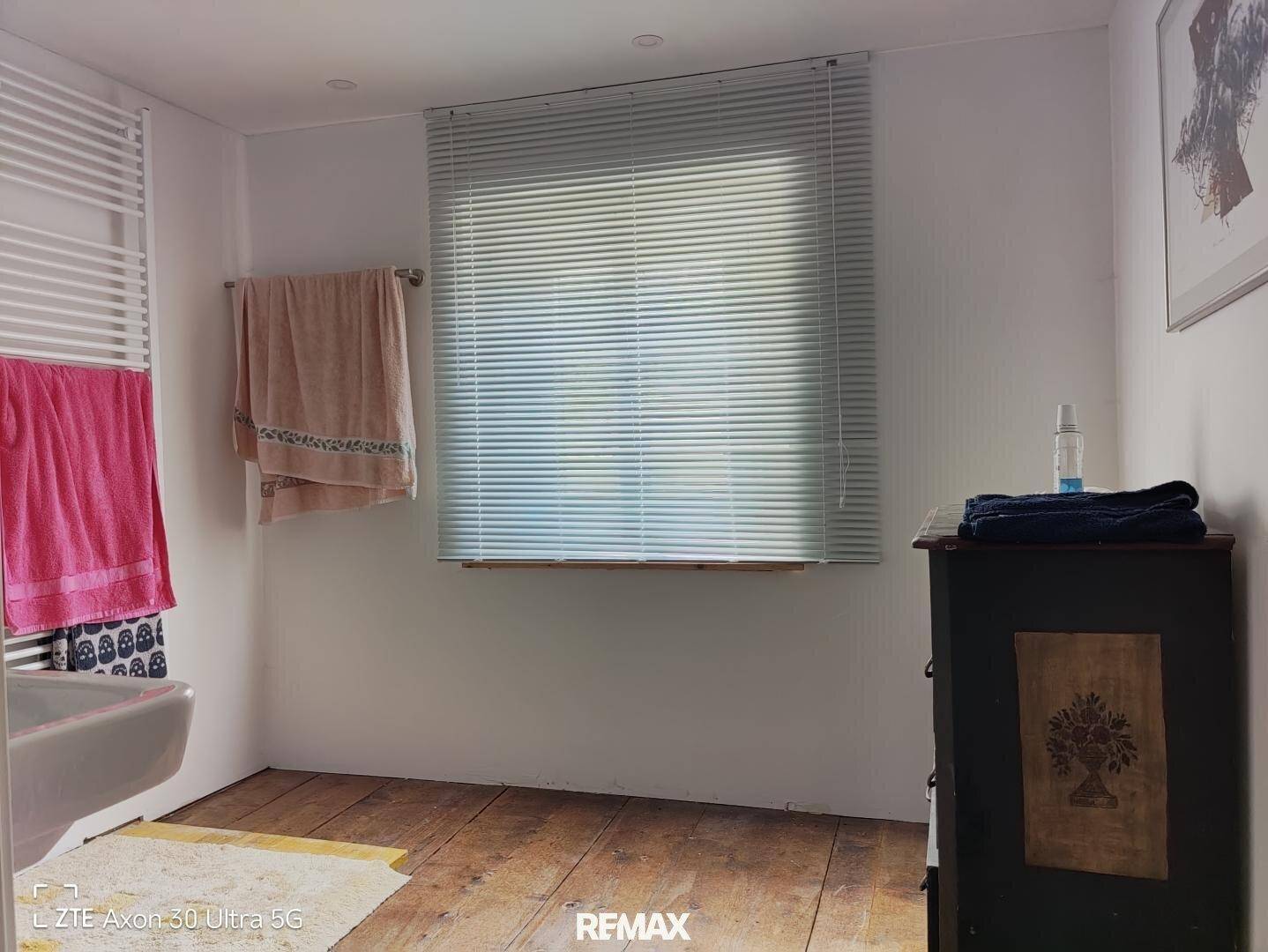 Helles Badezimmer mit Holzboden, Fenster und beheiztem Handtuchhalter.