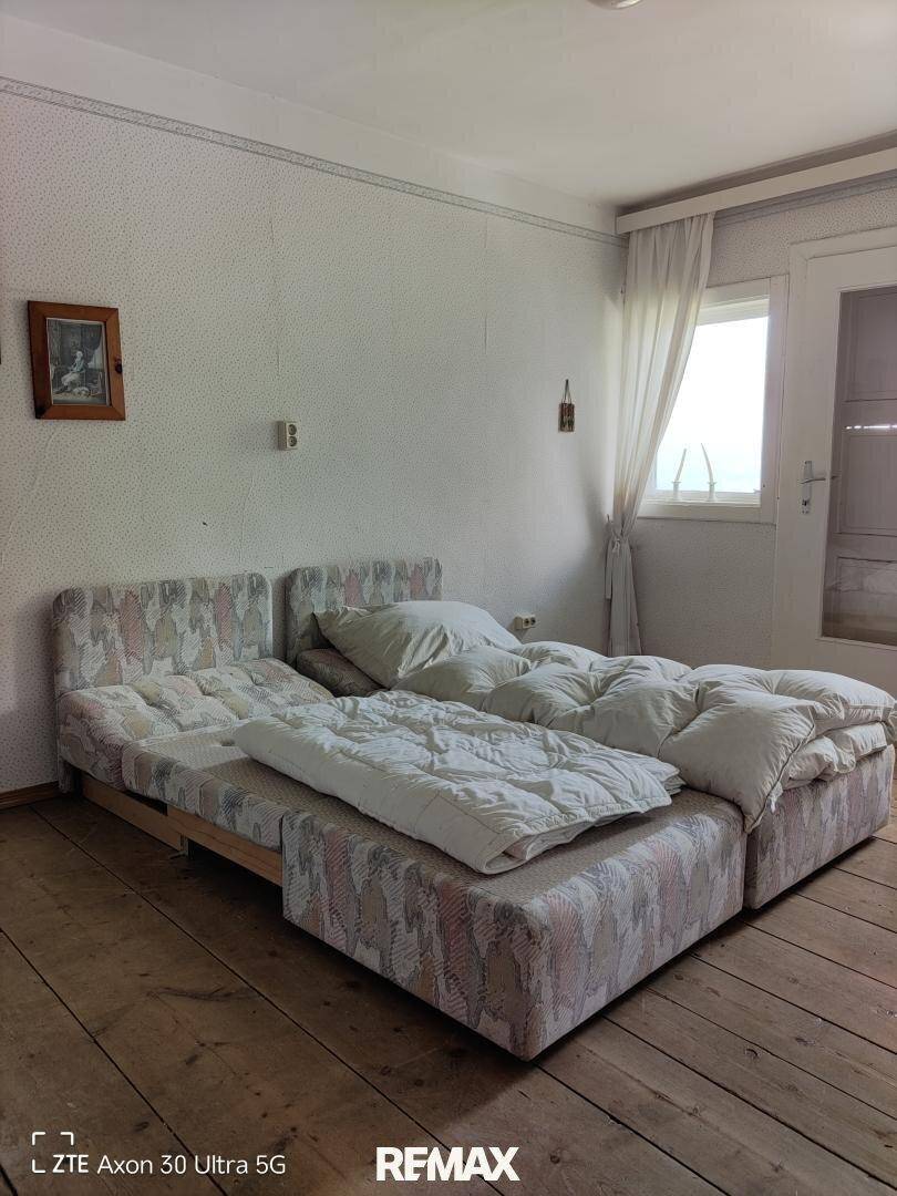 Schlafzimmer mit zwei Einzelbetten, Holzboden und Fenster.