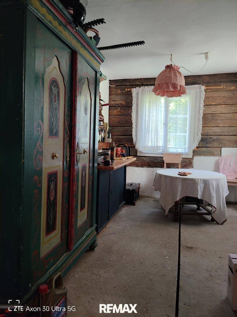 Rustikaler Raum mit Holzwänden, bemaltem Schrank und kleinem Tisch.