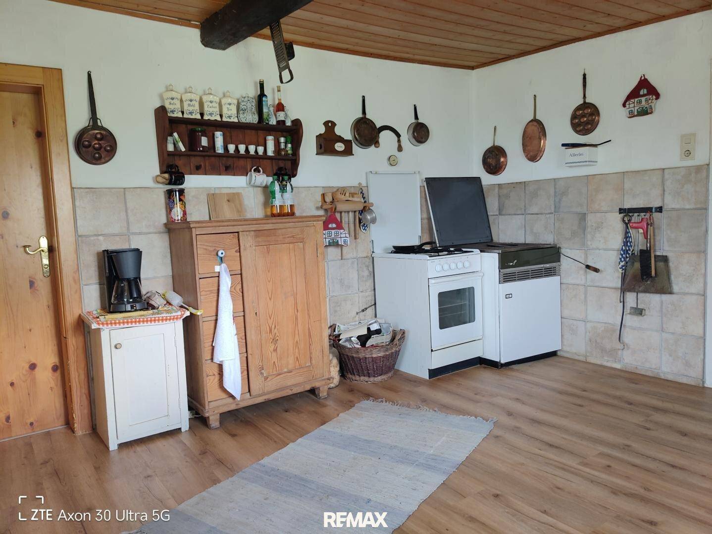 Einfache Küche im Landhausstil mit Holzschrank, Herd und traditionellen Utensilien.