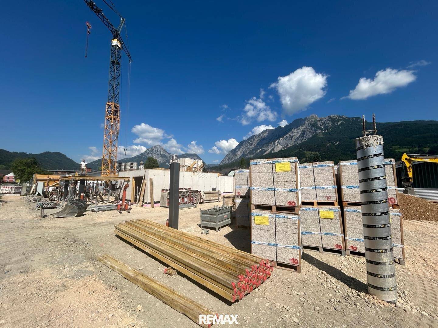 Baustelle mit Baumaterialien, Kran und Blick auf die umliegenden Berge.