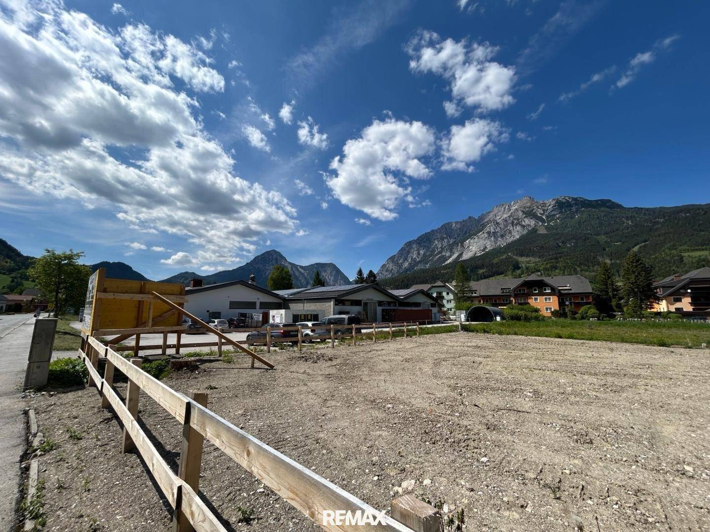 Freies Baugrundstück mit Holzzaun und weitem Blick auf die umliegende Berglandschaft.
