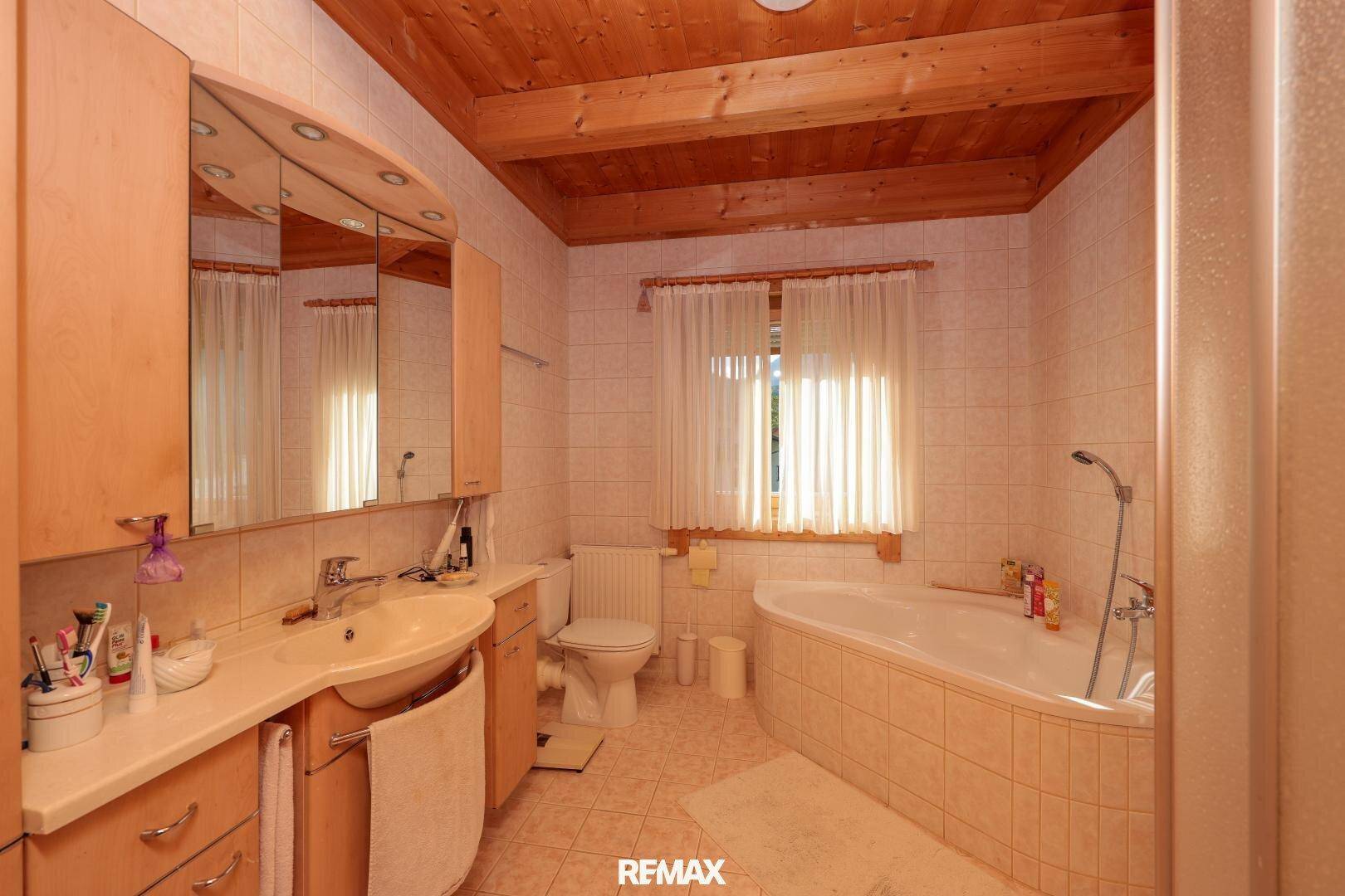 Geräumiges Badezimmer mit Eckbadewanne, Doppelwaschbecken und Holzdecke.
