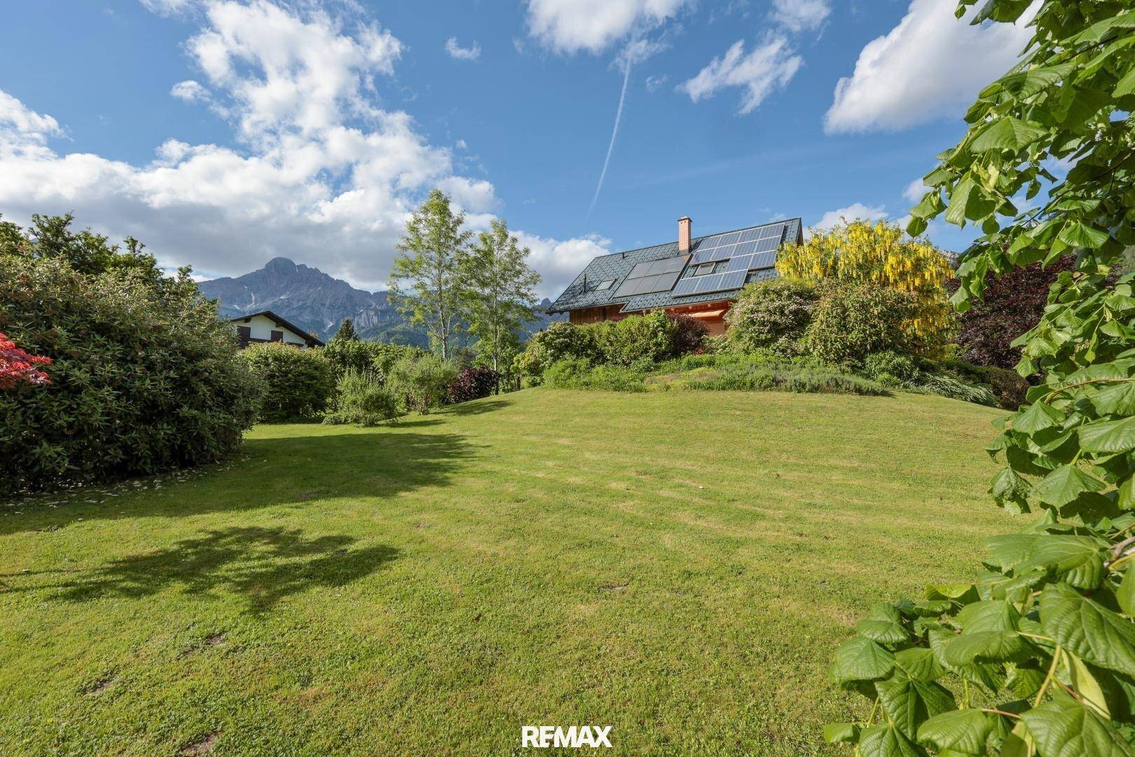 Großer, gepflegter Rasenbereich mit Blick auf das Holzhaus und die Berge im Hintergrund.