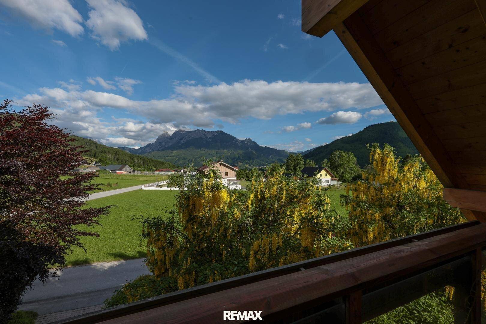 Panoramablick vom Balkon auf die umliegende Berglandschaft und grüne Wiesen.