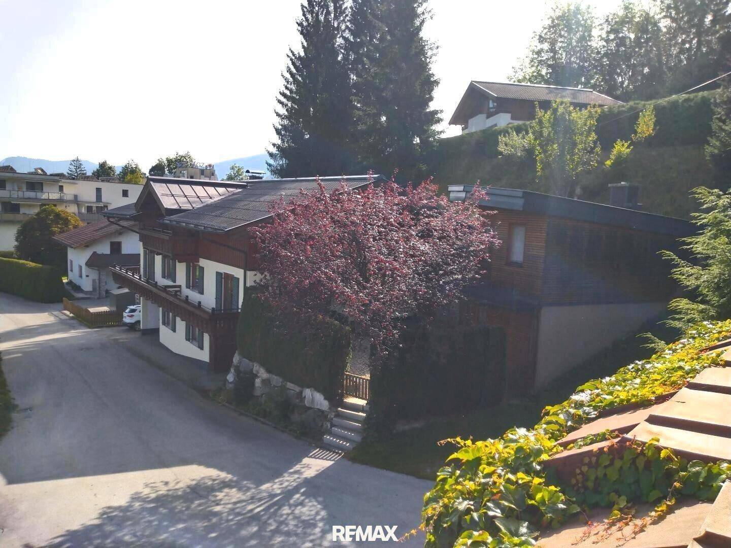 Ansicht des Anwesens von der Straße aus, mit traditionellem und modernem Gebäudeteil und grüner Umgebung.