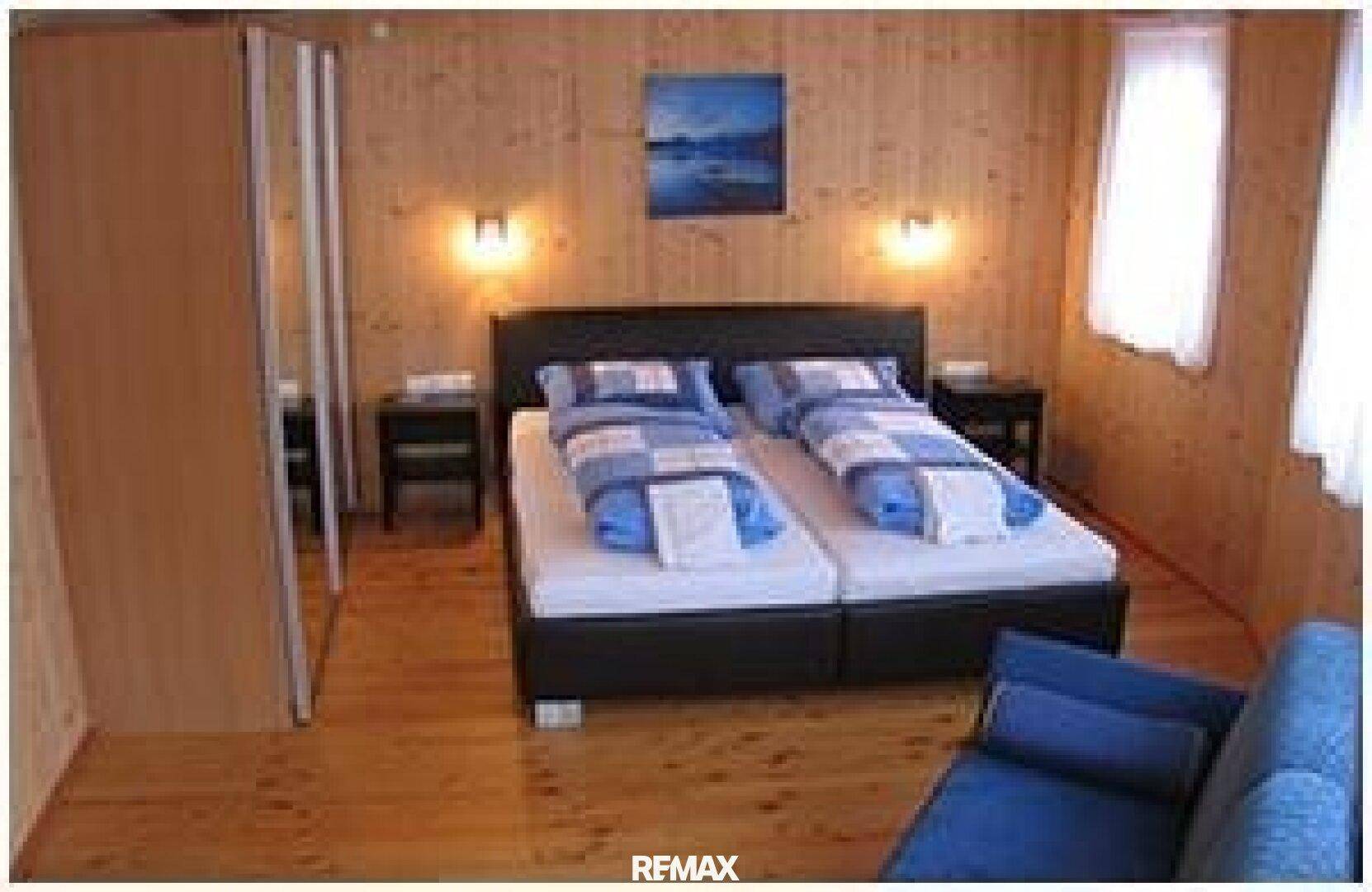 Gemütliches Schlafzimmer mit zwei Einzelbetten, Holzvertäfelung und Parkettboden im alpinen Stil.