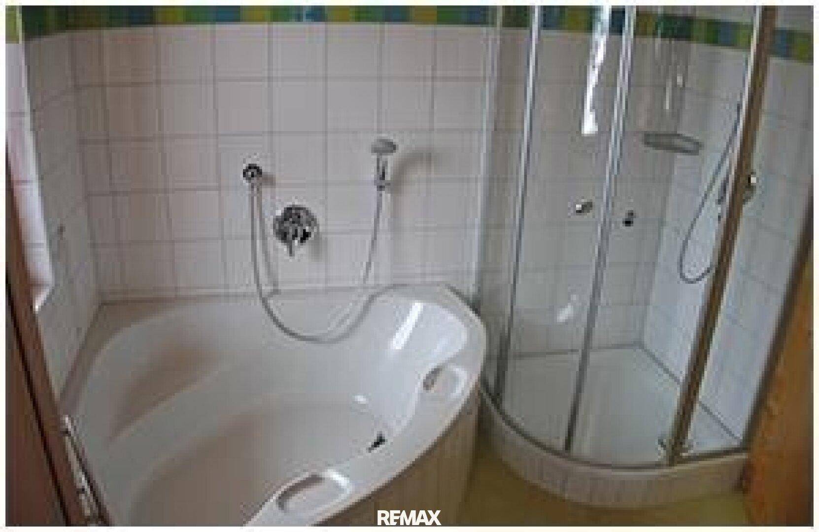 Badezimmer mit einer Eckbadewanne und einer separaten Duschkabine, gefliest in hellem Design.
