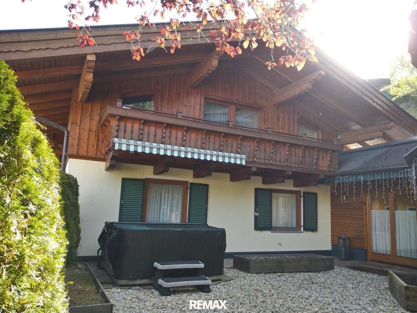 Gemütlicher Außenbereich mit Whirlpool und einem traditionellen Holzbalkon, umgeben von üppigem Grün.