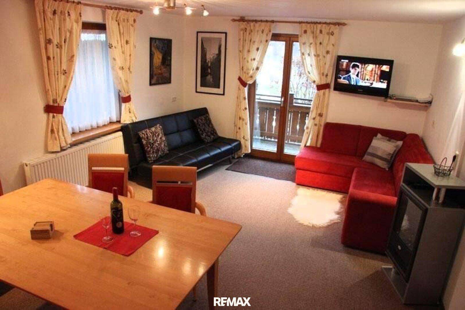 Gemütlicher Wohn-Essbereich mit Esstisch, Sofas und Zugang zu einem Balkon, ausgestattet mit Teppichboden.