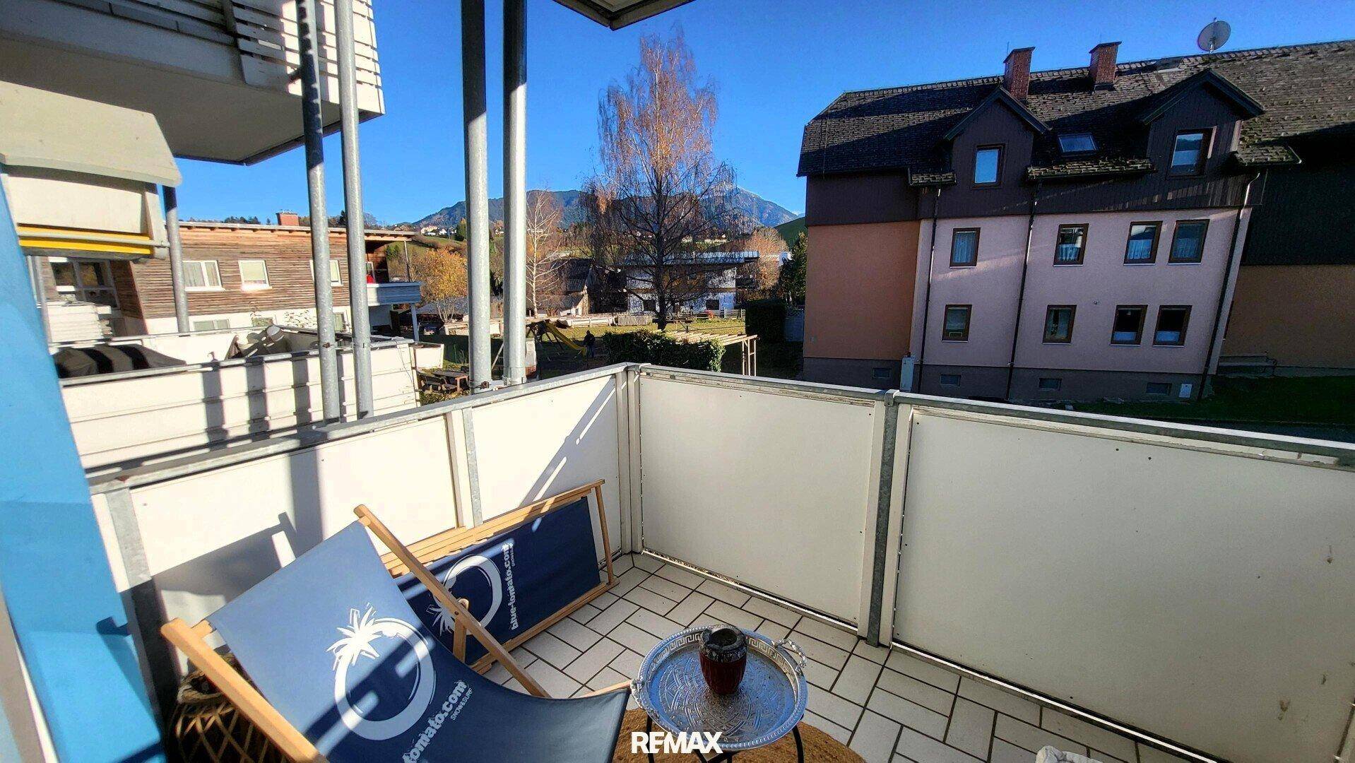 Sonniger Balkon mit Liegestuhl, Beistelltisch und Bergblick.