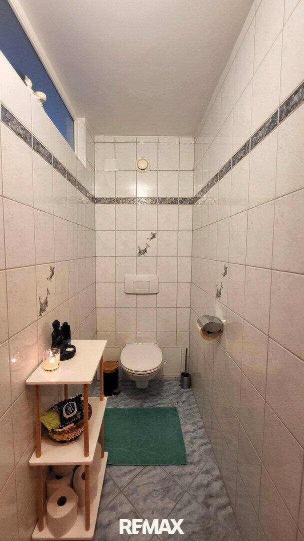 Separate Toilette mit Fliesen, WC und kleinem Oberlichtfenster.