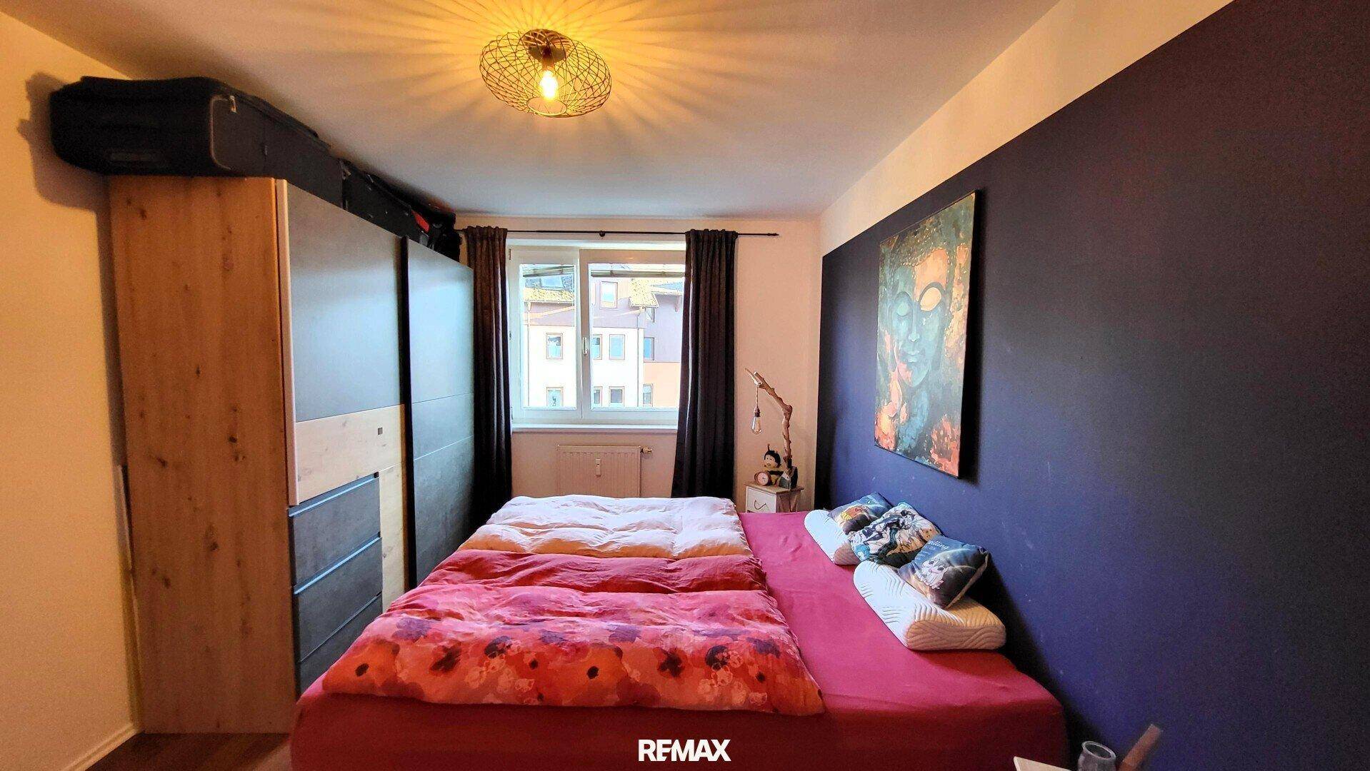 Geräumiges Schlafzimmer mit Palettenbett, Kleiderschrank und Fenster.