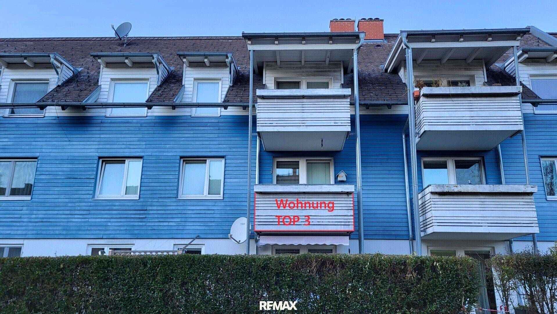 Fassade eines Mehrfamilienhauses mit blauer Holzverkleidung und Balkonen.
