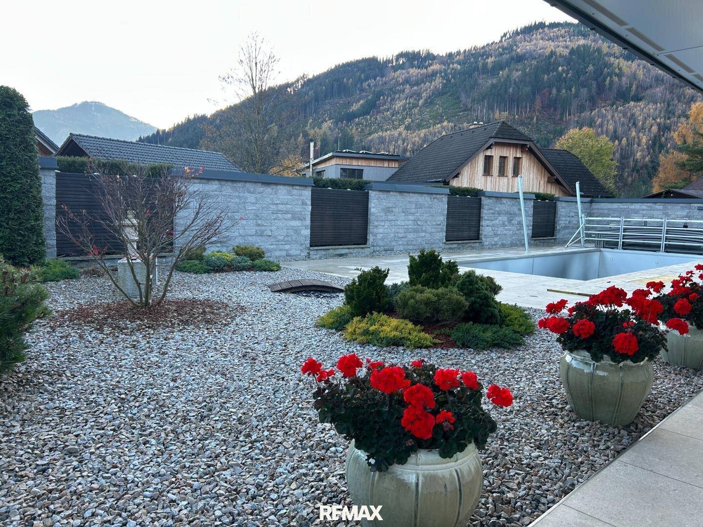 Gepflegter Gartenbereich mit Zierpflanzen, Kiesflächen und einem sichtbaren Pool im Hintergrund.