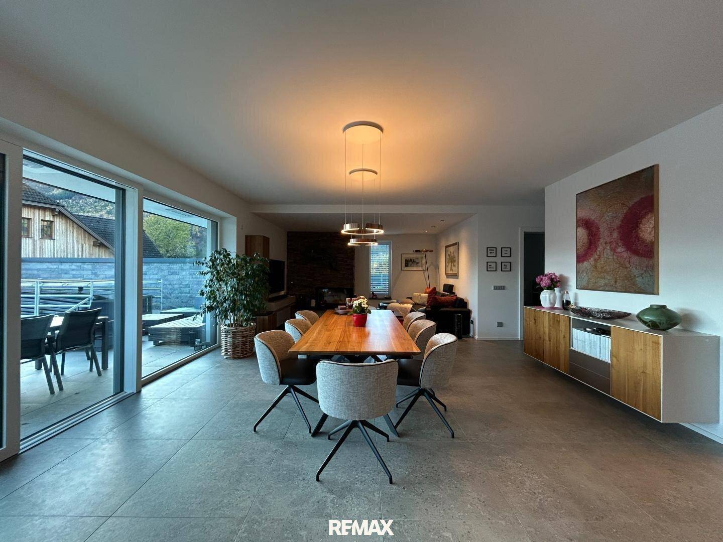 Heller Wohn-Essbereich mit großem Esstisch, modernen Leuchten und Zugang zur Terrasse.
