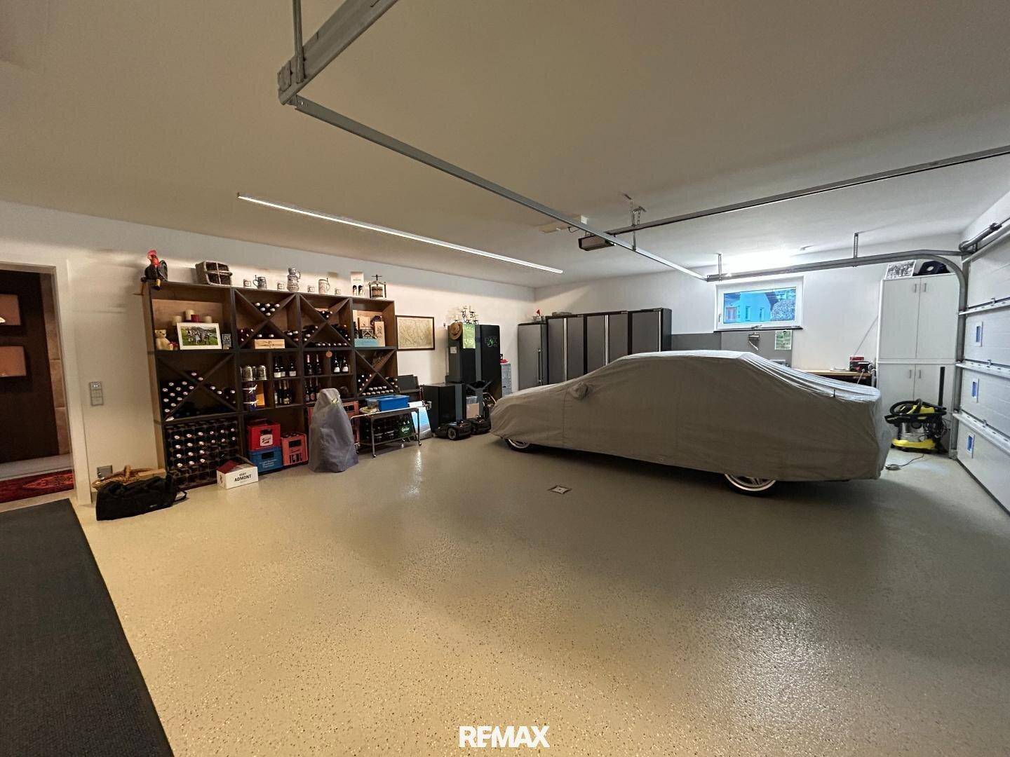 Geräumige Garage mit viel Stauraum, Weinregalen und einem geparkten Fahrzeug.