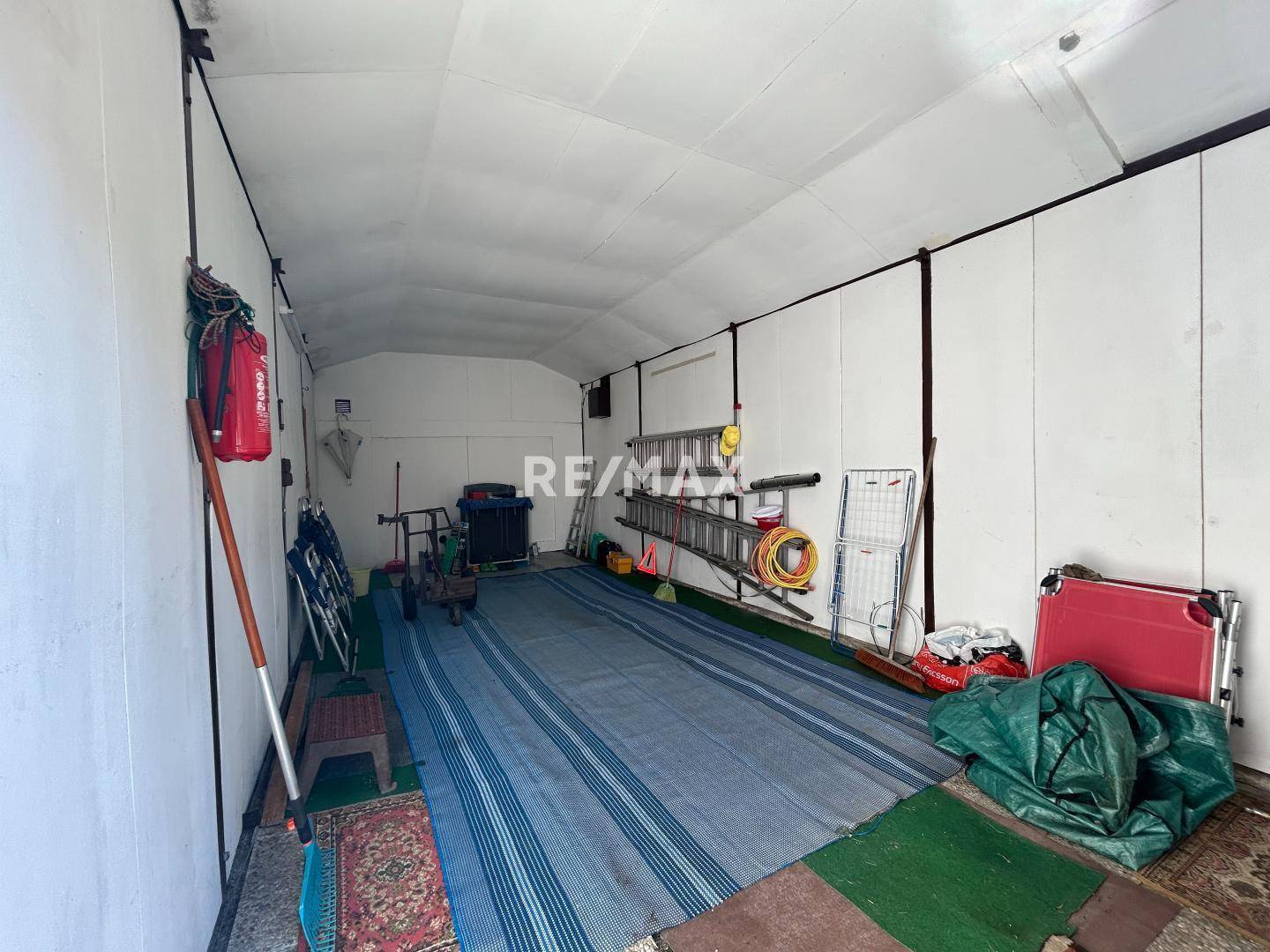 Geräumiger Innenraum einer Garage, genutzt als Lagerfläche mit verschiedenen Geräten und Leitern.