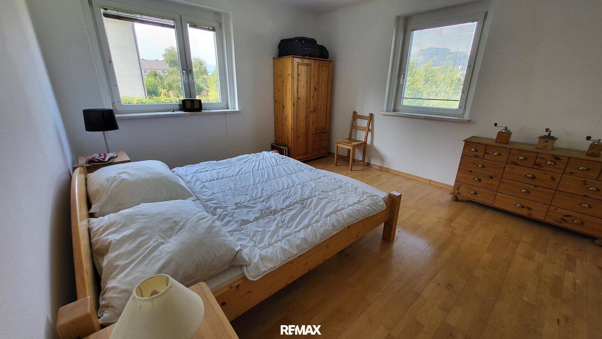 Schlafzimmer mit Doppelbett, Holzschrank und Kommode, sowie Holzboden.
