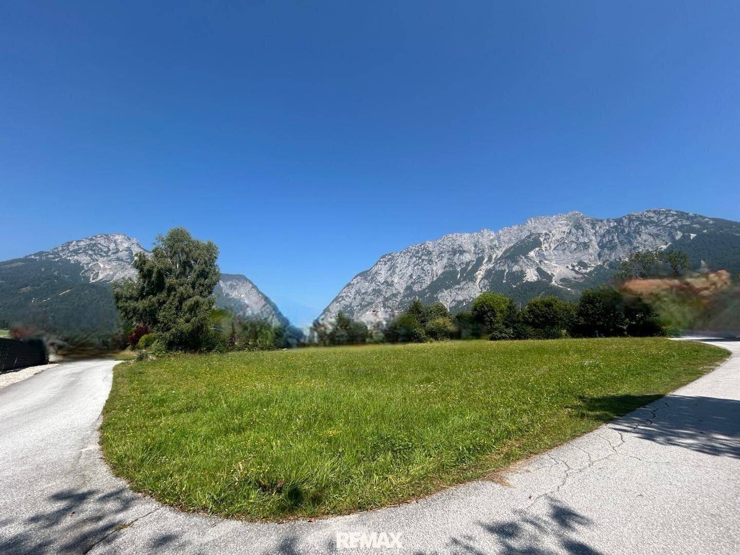 Idyllische grüne Landschaft mit zwei markanten Berggipfeln in der Ferne, umgeben von üppiger Natur.