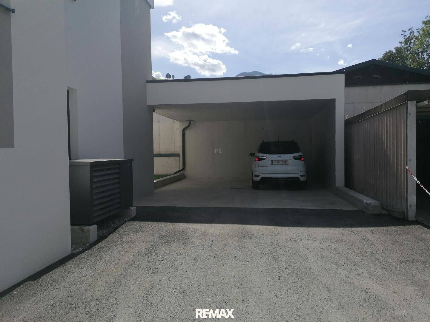 Überdachter Parkplatz (Carport) mit einem geparkten Auto und Blick auf die umliegenden Berge.