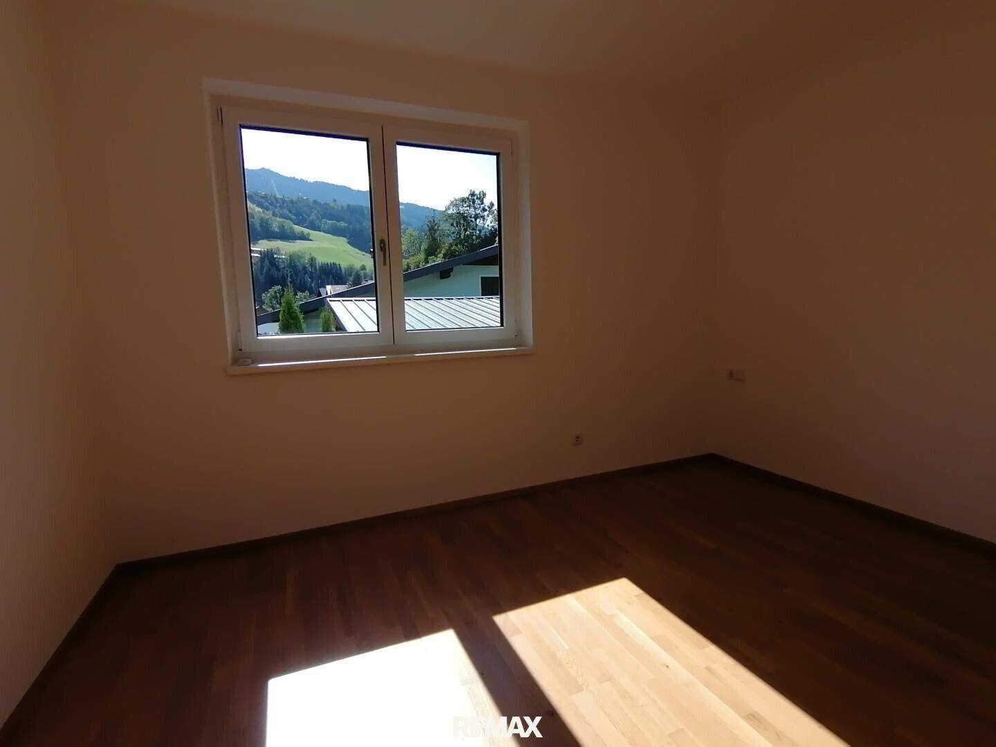 Schlafzimmer mit Parkettboden und Fenster, das einen sonnigen Blick auf die Landschaft bietet.