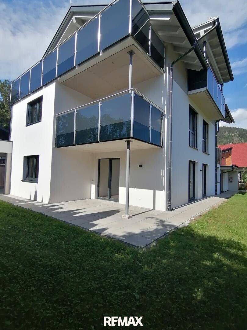 Moderne Gebäudefassade mit Balkonen und einer gepflegten Rasenfläche im Vordergrund.