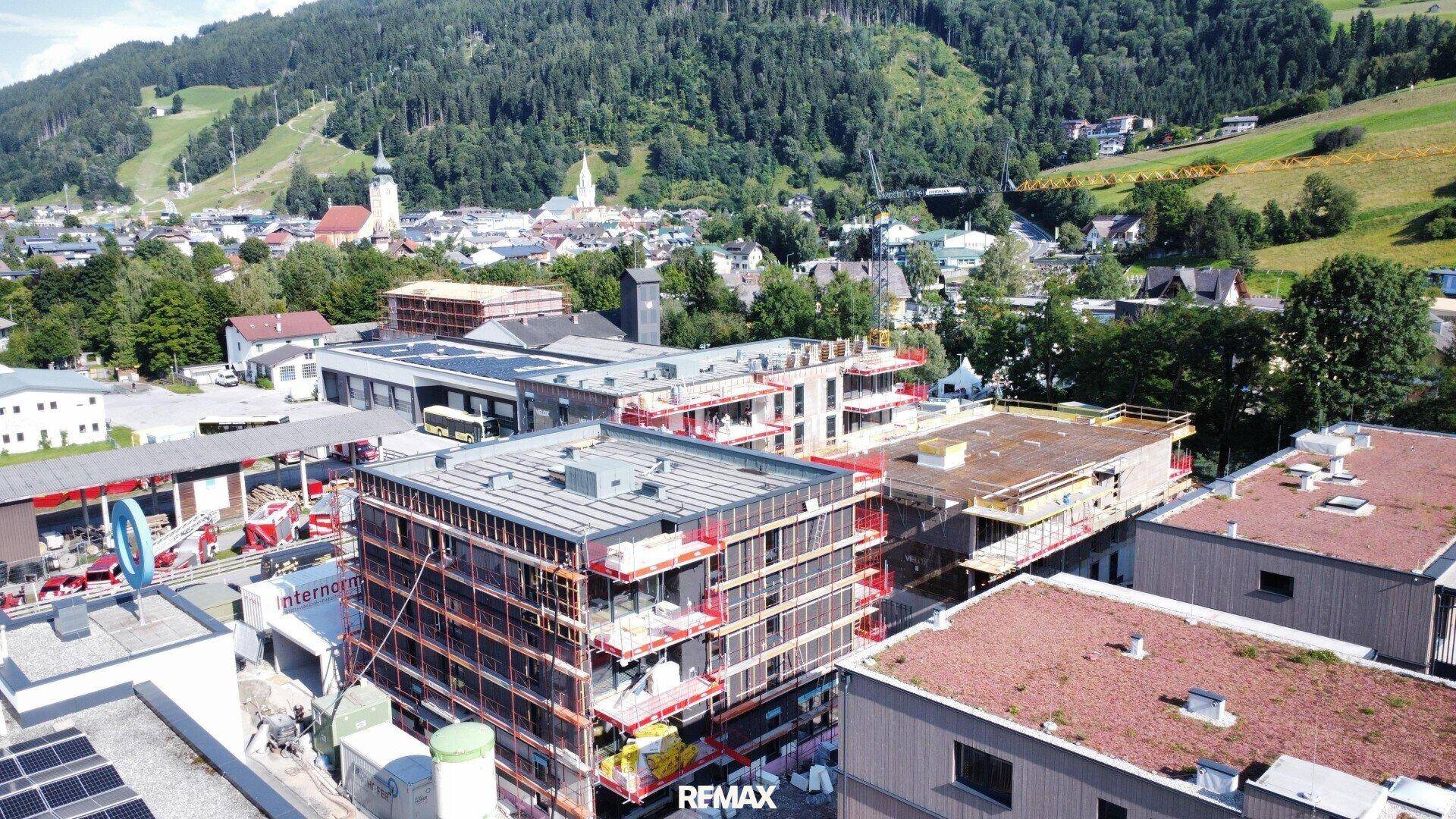 Luftaufnahme einer Baustelle für Wohngebäude mit Blick auf die Stadt und die umliegenden Berge.