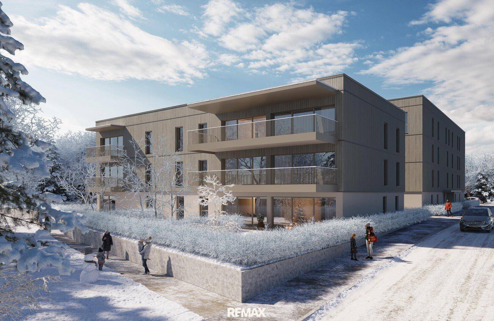 Ansicht eines modernen Wohngebäudes mit Balkonen und gepflegter Außenanlage im Winter.