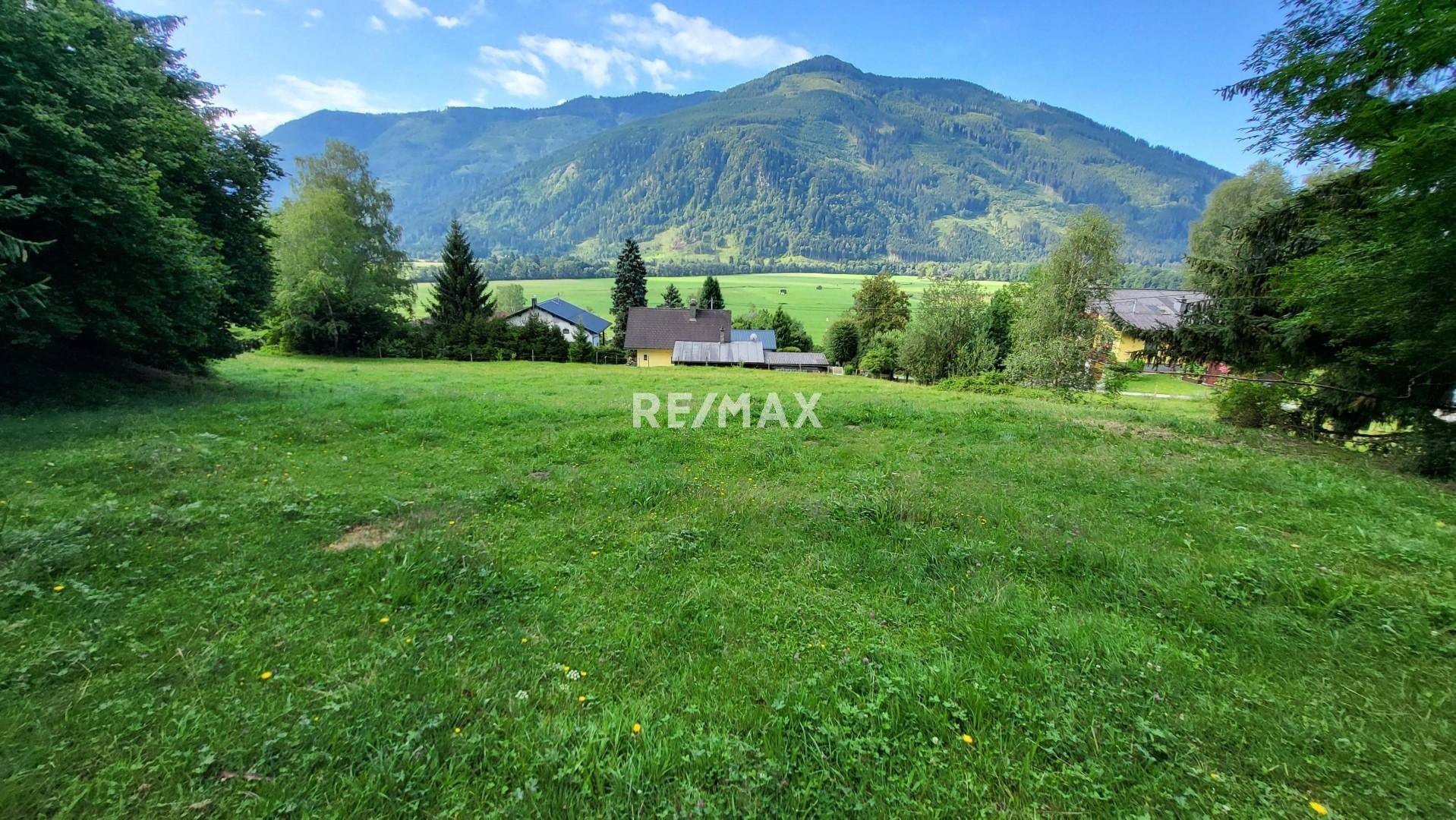 Großzügige Grünfläche mit Panoramablick auf die Berge und einige Häuser in der Ferne.