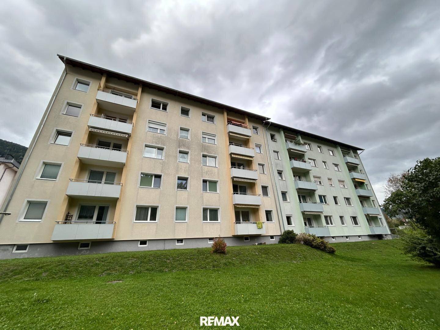 Ansicht des Mehrfamilienhauses mit mehreren Balkonen und einer weitläufigen Grünfläche davor.