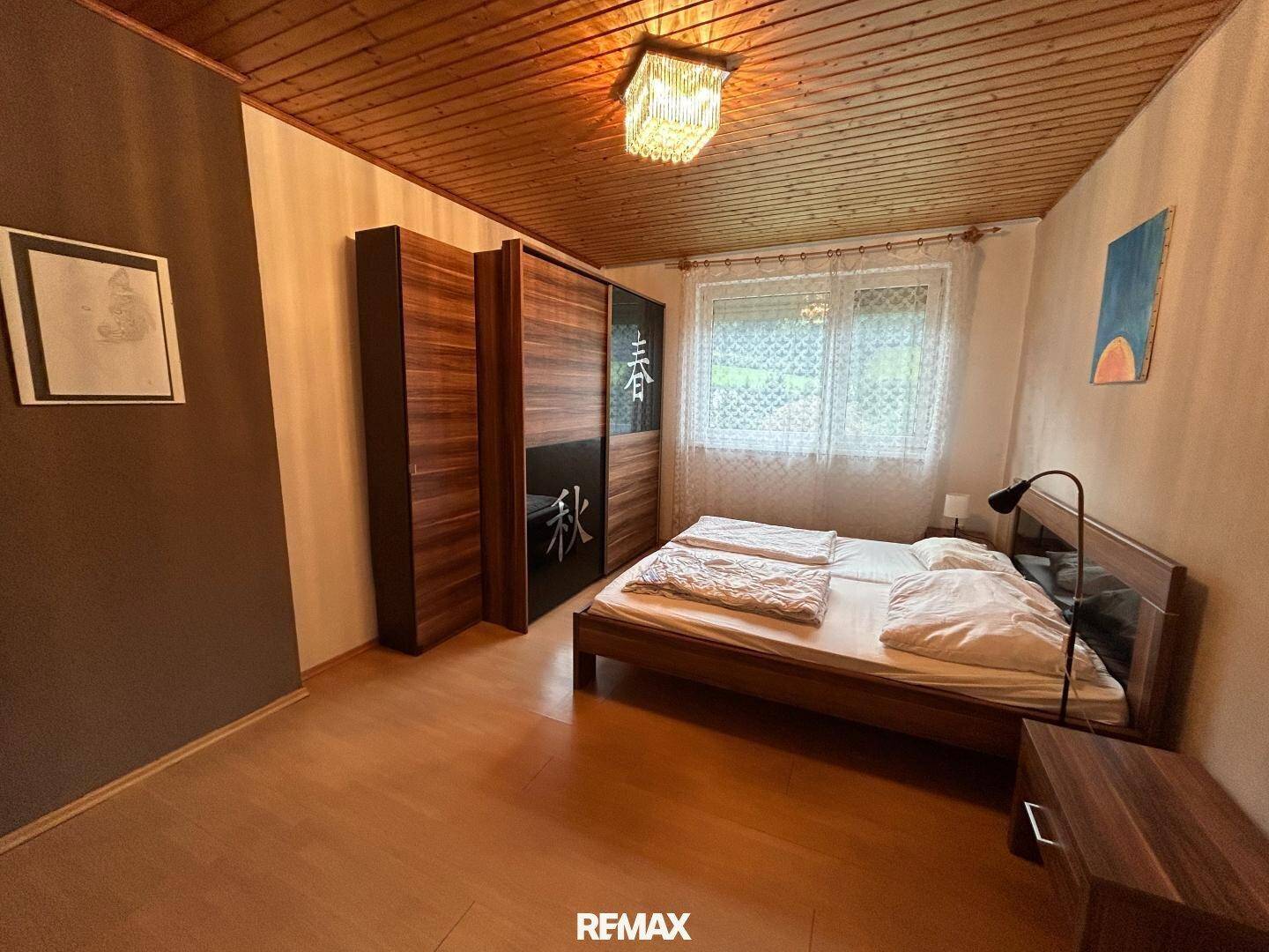 Schlafzimmer mit Fenster, das viel Tageslicht hereinlässt, und einem großen Kleiderschrank.