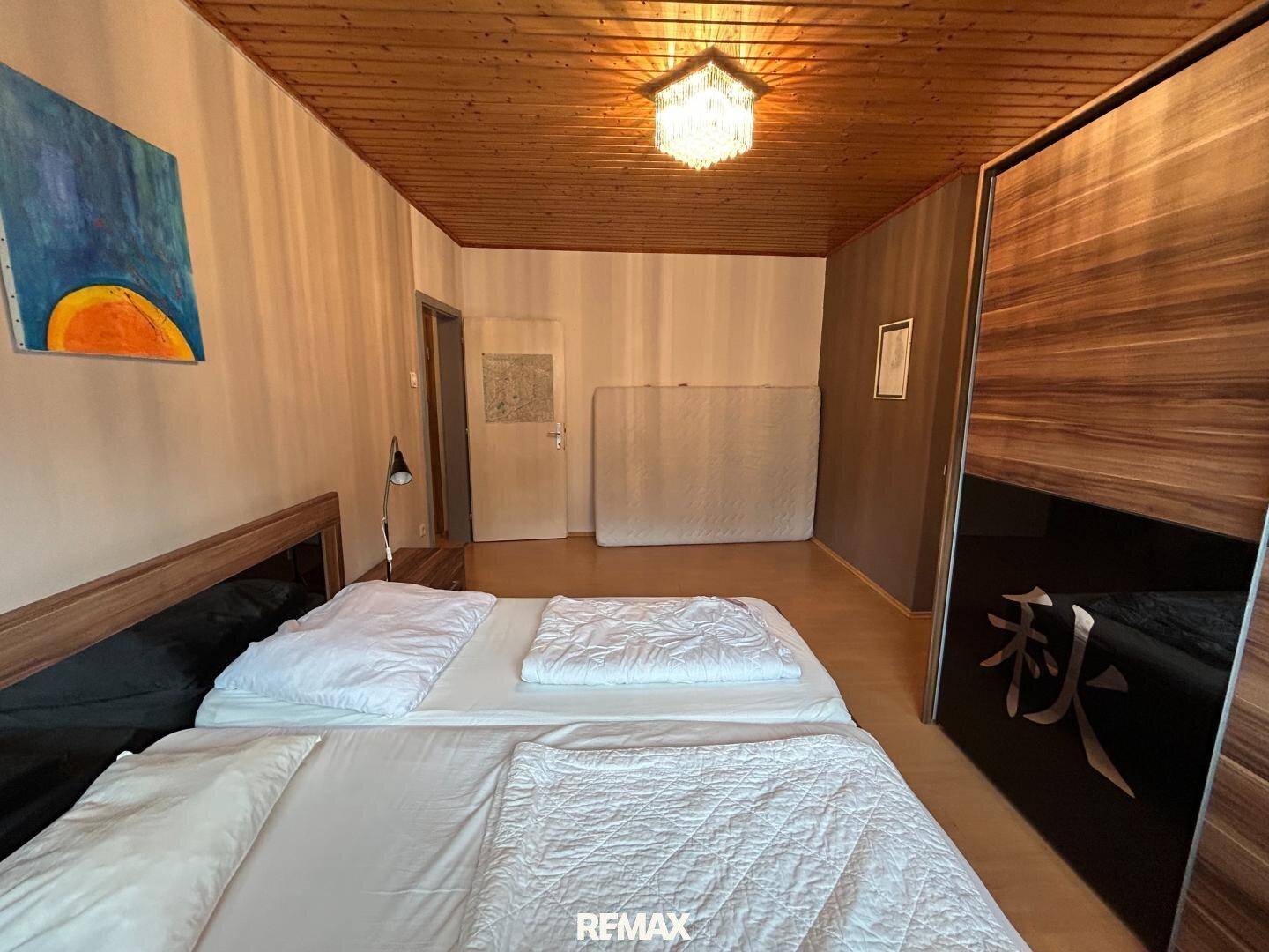 Geräumiges Schlafzimmer mit Doppelbett, großem Kleiderschrank und Holztäfeldecke.