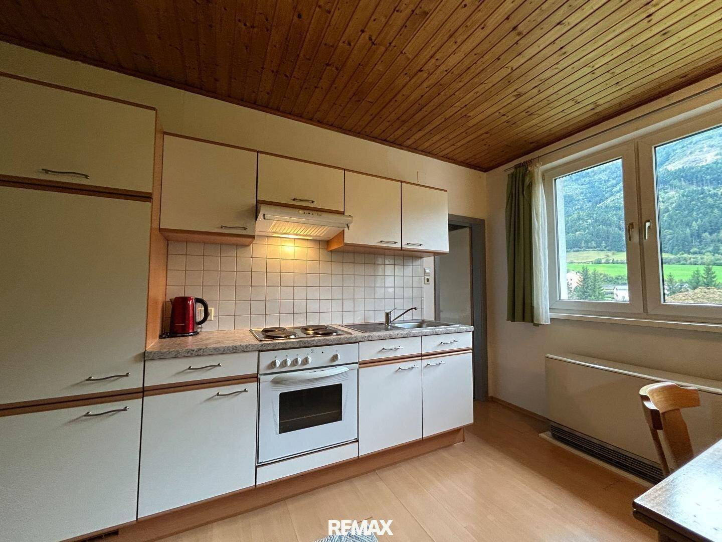 Küchenzeile mit Fenster und Blick auf die grüne Landschaft, ausgestattet mit Herd und Spüle.