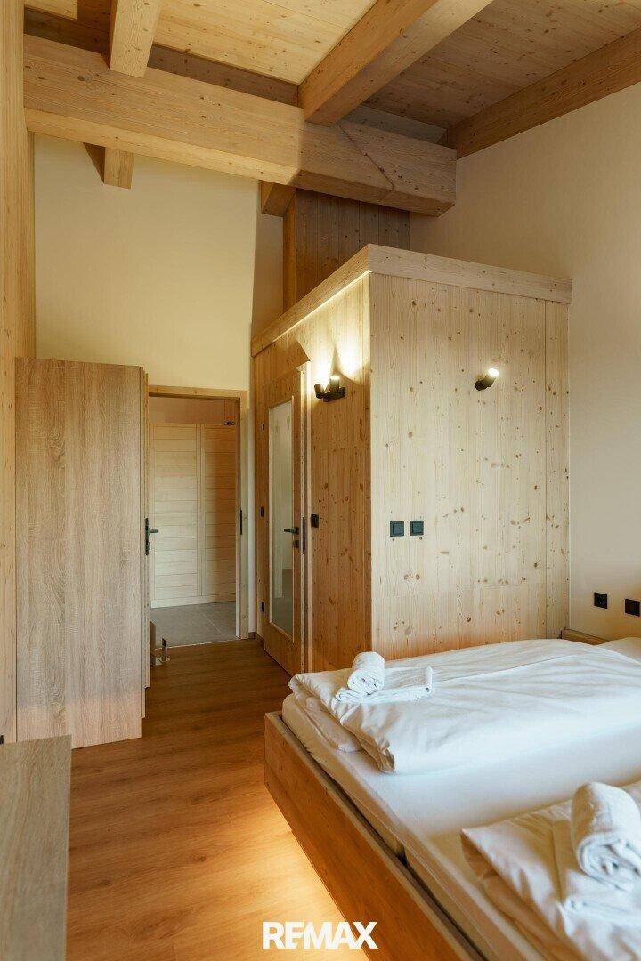 Gemütliches Schlafzimmer mit Holzbett, Holzbalkendecke und integriertem Schrankbereich.