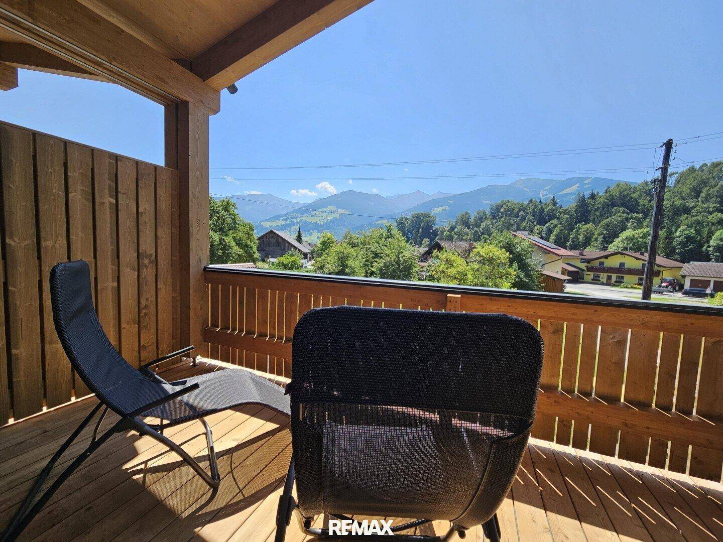 Sonniger Balkon mit Liegestühlen und weitem Blick auf die umliegende Berglandschaft.