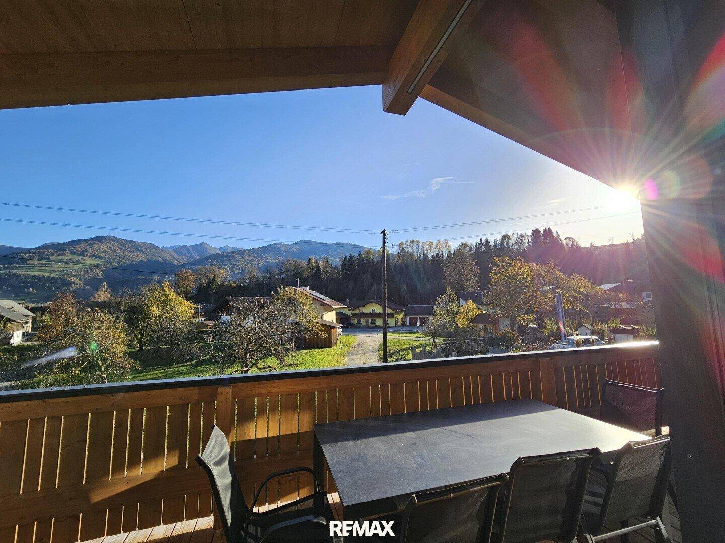 Geräumiger Balkon mit Holzboden und Esstisch, ideal für Mahlzeiten mit Bergblick.