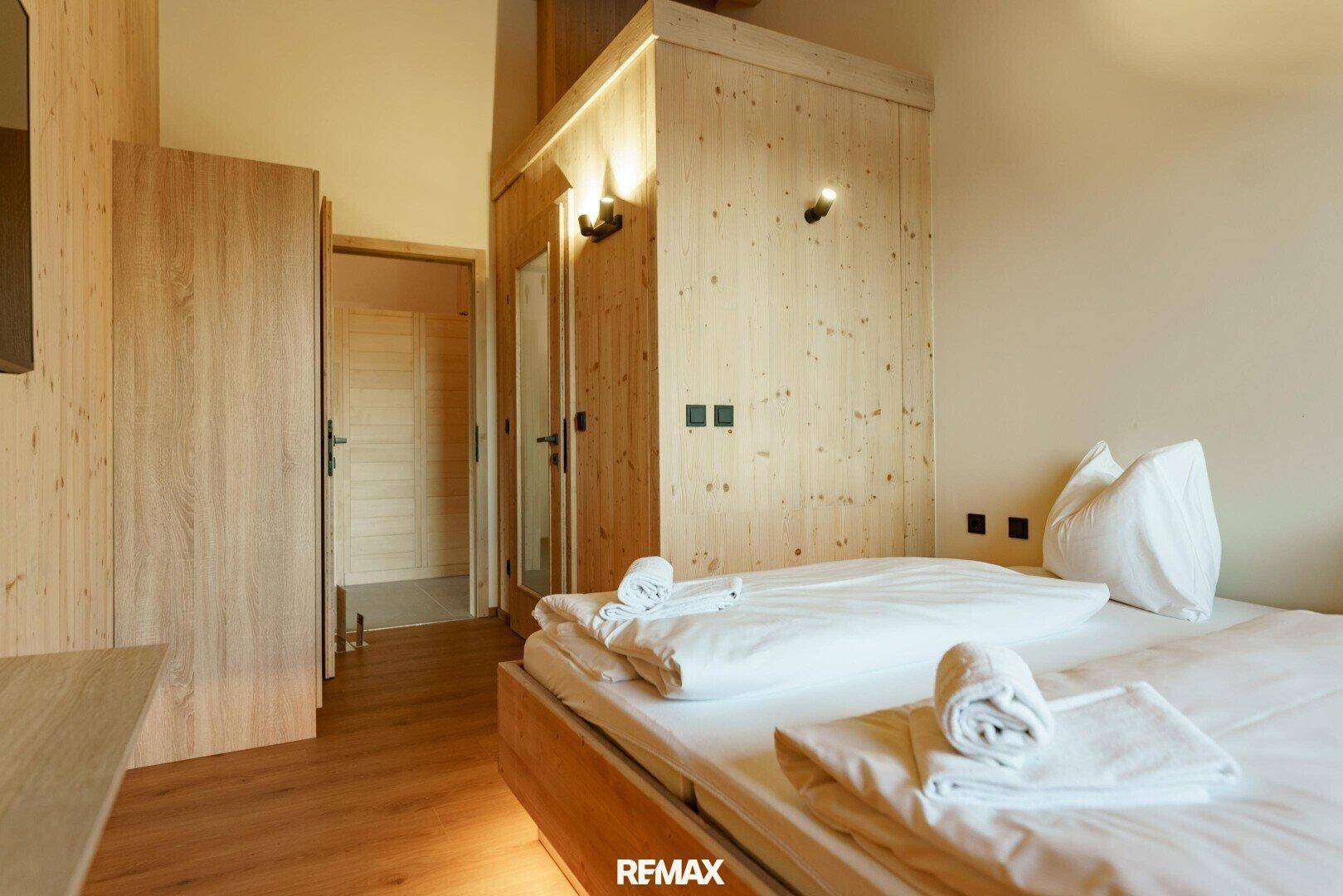 Helles Schlafzimmer mit Holzbett, Holzboden und integriertem Schrankbereich.