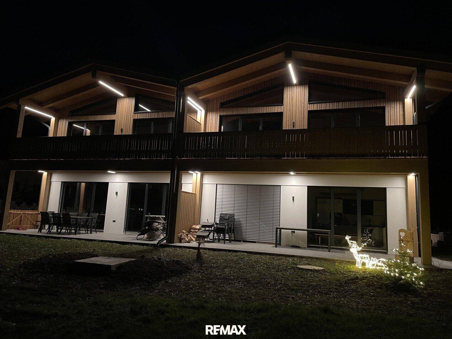 Außenansicht des Gebäudes bei Nacht mit beleuchteten Terrassen und Balkonen.