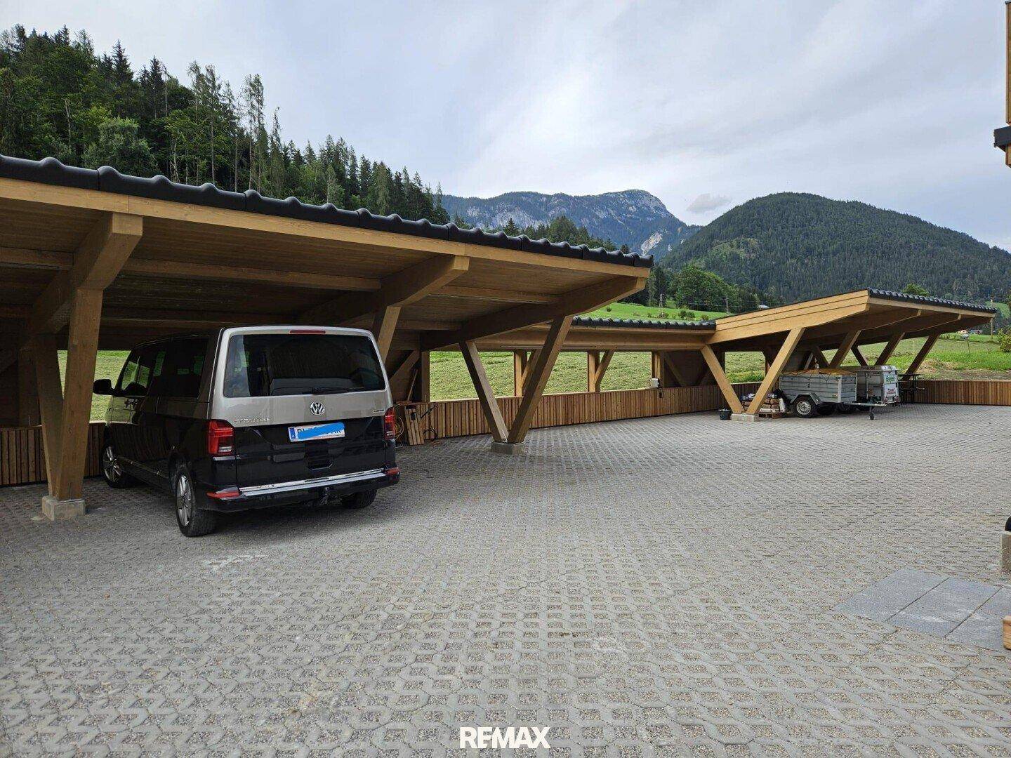 Überdachte Parkplätze (Carports) vor einem Chalet mit Bergblick.