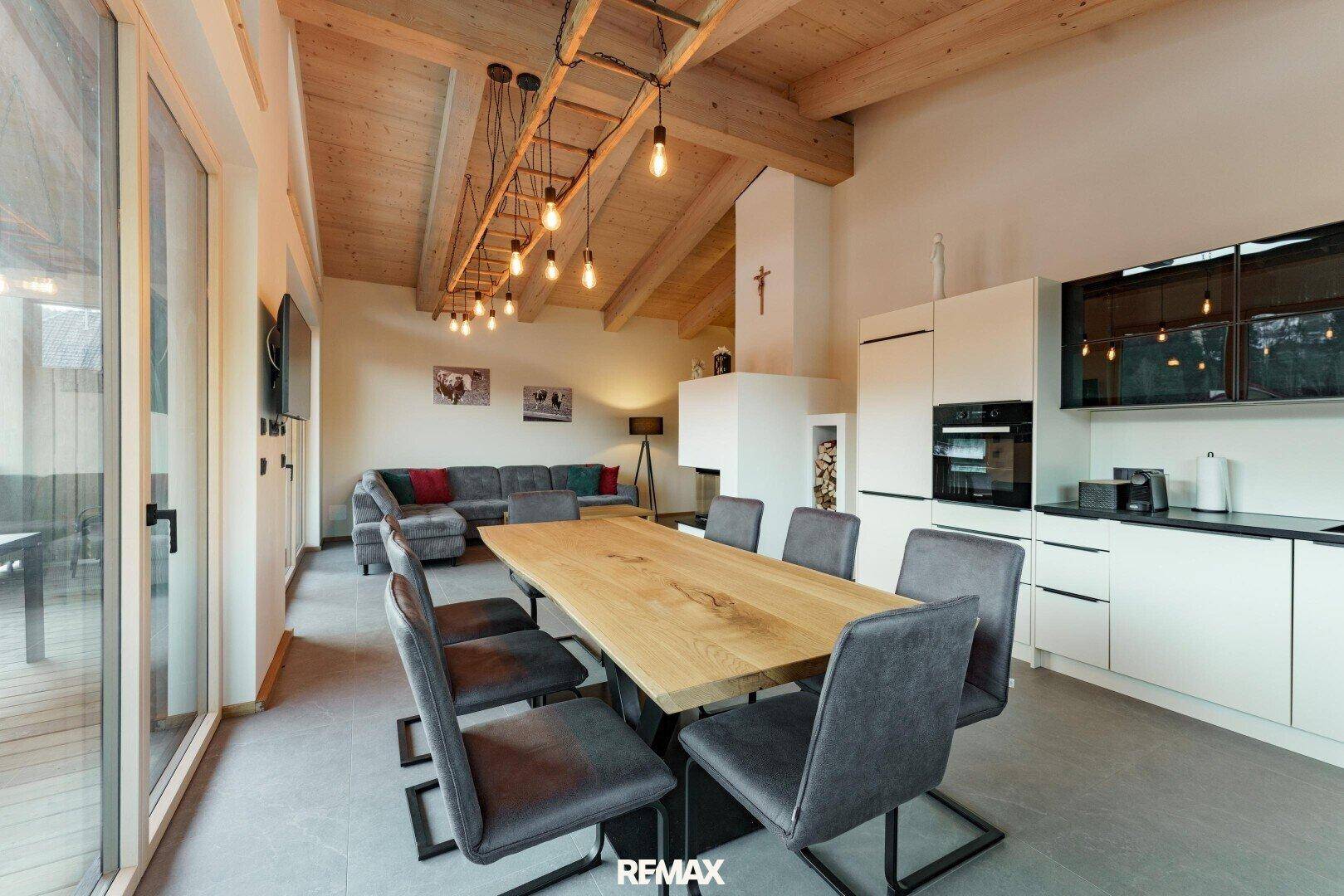 Heller offener Wohn-Essbereich mit moderner Küche, Holzbalkendecke und Zugang zur Terrasse.