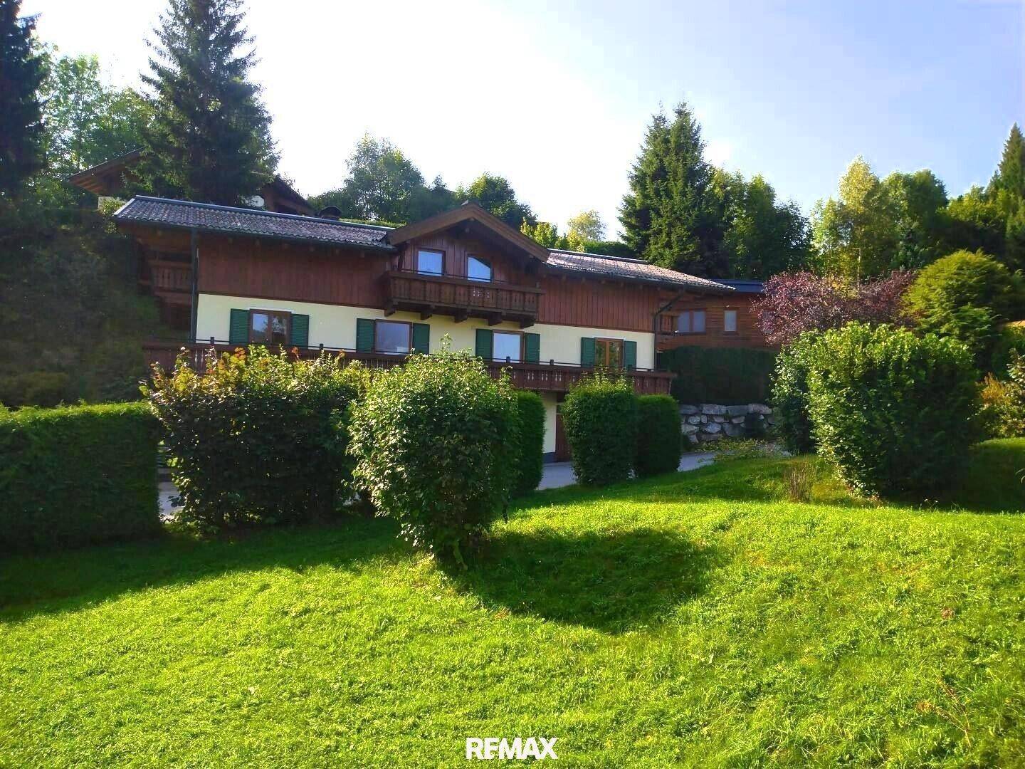 Weitläufiger Garten mit gepflegtem Rasen und Sträuchern vor dem traditionellen Haus in sonniger Lage.