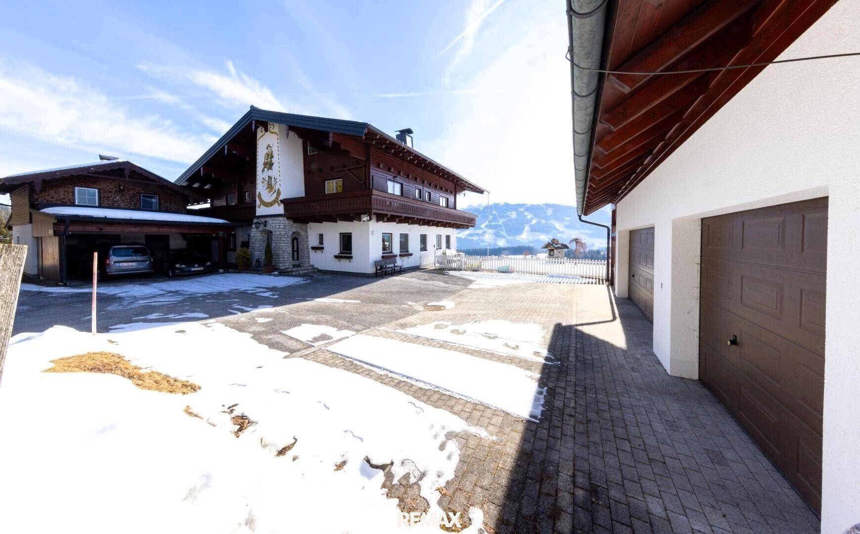 Traditionelles Haus mit Garagen und gepflasterter Auffahrt in verschneiter Umgebung.