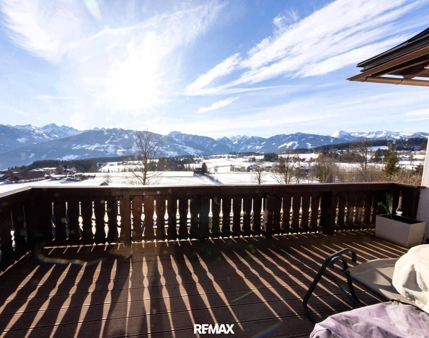 Große Holzterrasse mit weitem Blick über die verschneite Tal- und Berglandschaft.